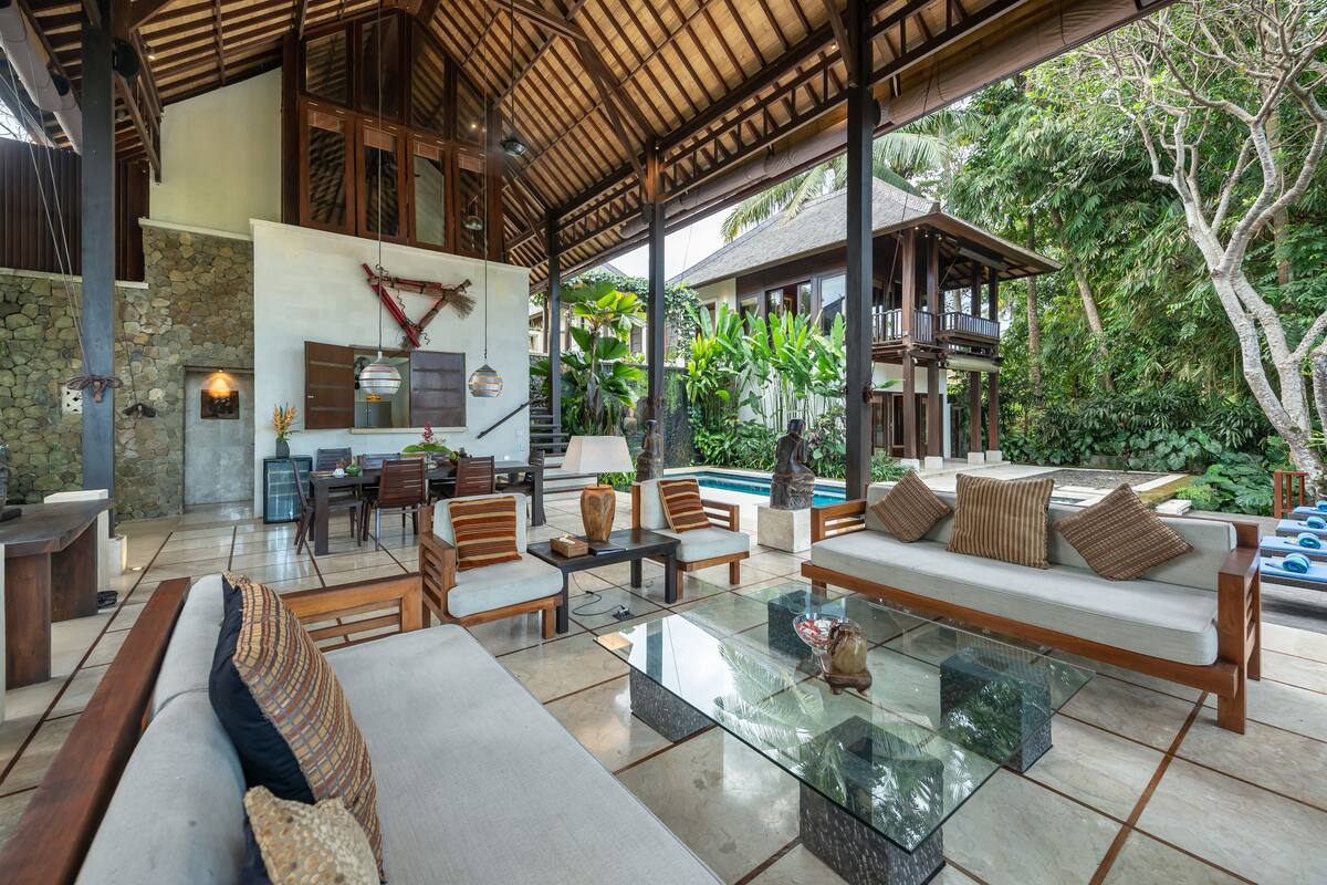 A spacious outdoor lounge area with a glass coffee table, cushioned seating, and a stone wall backdrop.