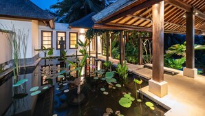 A serene outdoor pool area with water lilies, wooden pergolas, and tropical plants. - Villa Vajra (Ubud)