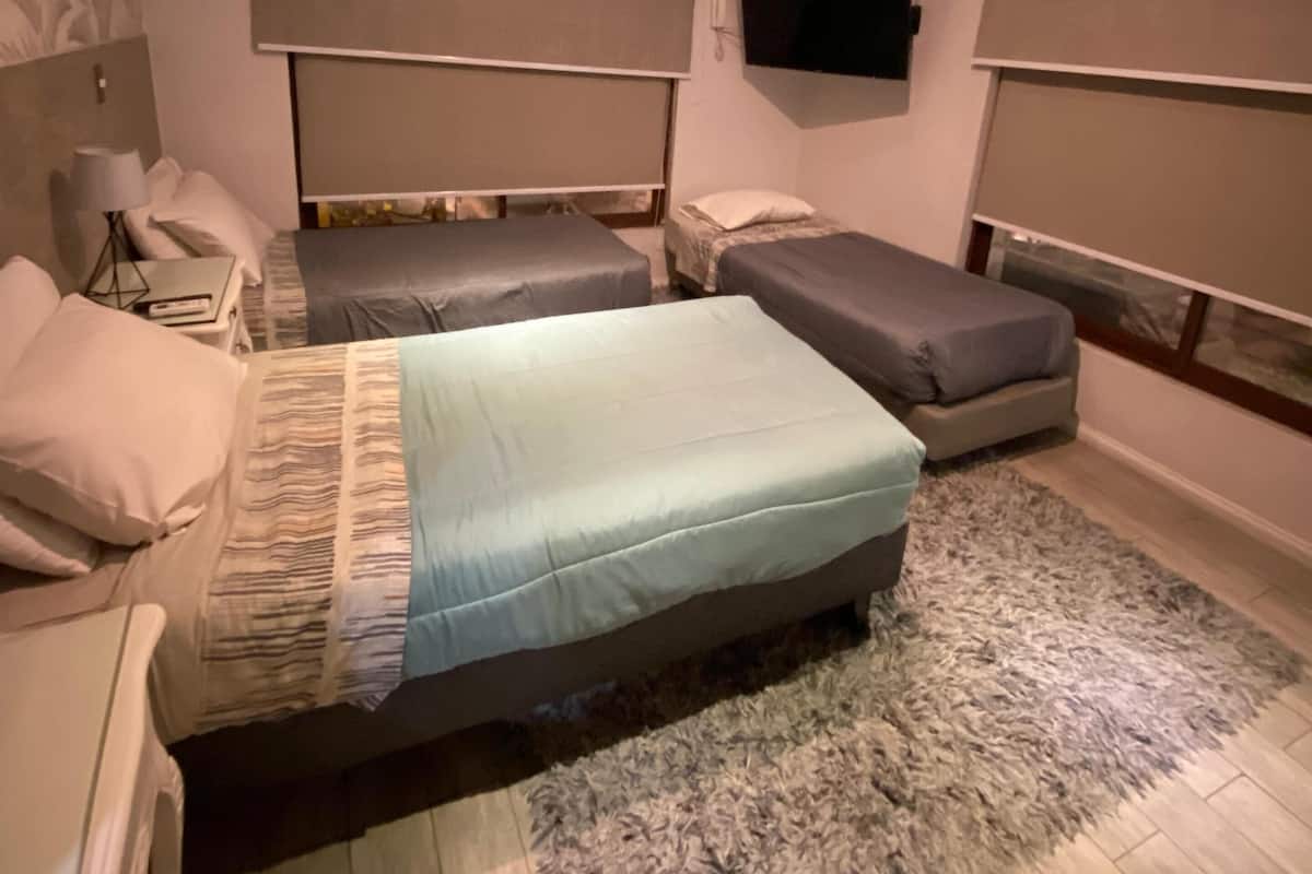 A bedroom with two beds, a TV, and a desk.
