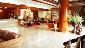 A spacious lobby with a reception desk, comfortable seating areas, and a large decorative pillar. - Tapae Place Hotel (Chiang Mai)