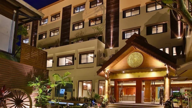 A multi-story hotel with a traditional architectural design, featuring a prominent entrance with a decorative ceiling and a large circular emblem. - Tapae Place Hotel (Chiang Mai)