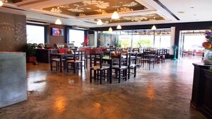A spacious restaurant with a high ceiling, pendant lighting, and a central seating area with tables and chairs. - Tapae Place Hotel (Chiang Mai)