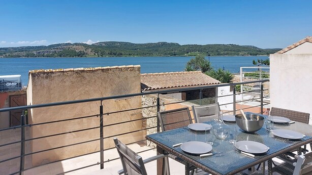 A terrace with a table set for dining, overlooking a body of water and hills. - La Maison de l'Etang by Interhome (Gruissan)