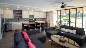 Una cocina moderna con armarios blancos, un comedor con mesa y sillas, y una sala de estar con sofá y una mesa de centro.