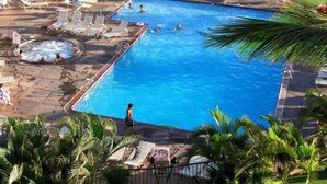 Una gran piscina al aire libre con sillones de descanso y zona de hidromasaje.