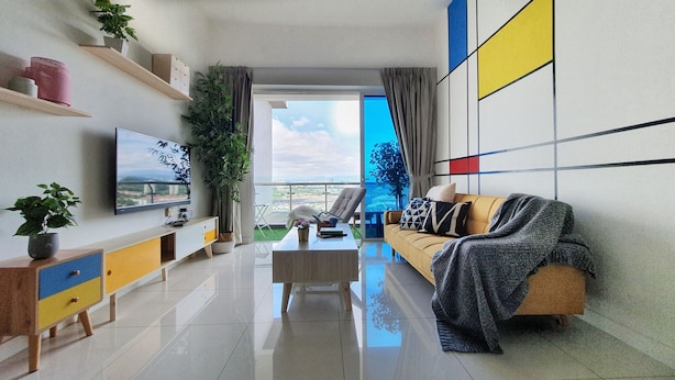 A modern living room with a flat-screen TV, a sofa, a coffee table, and a balcony with a view. - Teiw Family Homestay at Skypod Residence Puchong (Puchong)