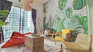 A living room with a large window, a giraffe decoration, a yellow chair, and a wall mural of leaves. - Teiw Family Homestay at Skypod Residence Puchong (Puchong)