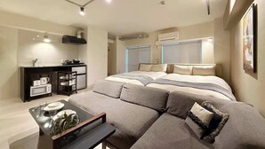 A modern bedroom with a large bed, a sofa, a small kitchenette, and a dining area. - ORIGAMINN 601 by b hotel - 5 mins PeacePark (Hiroshima City)