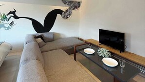 Ein modernes Wohnzimmer mit einer Couch, einem Couchtisch, einem Flachbildfernseher und Wanddekoration.