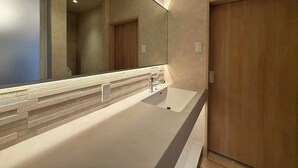 Une salle de bain moderne avec un grand miroir, un lavabo blanc et des portes en bois.