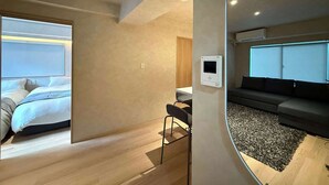 Une chambre d’hôtel moderne avec un lit, un petit bureau, un canapé et une grande fenêtre.