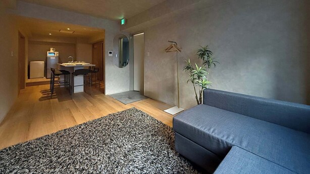 Un salon moderne avec un canapé, un coin repas comprenant une table et des chaises, et un espace cuisine équipé d’un réfrigérateur et d’un four à micro-ondes.