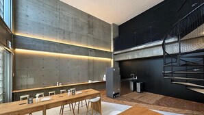 Eine moderne Küche mit einem langen Holztisch, Barhocker und einer schwarzen Treppe.