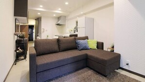 A modern living room with a sectional sofa, a small side table, and a kitchen area in the background.