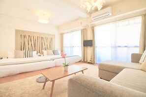 A modern living room with a sofa set, a coffee table, and a TV mounted on the wall. - Spacious & Relaxing just 4 blocks to Peace Park (Hiroshima City)