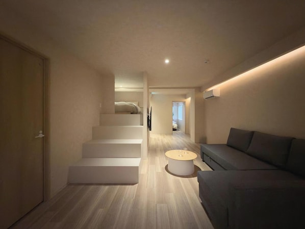 A modern interior with a staircase leading to a bedroom, a sofa, and a round coffee table.