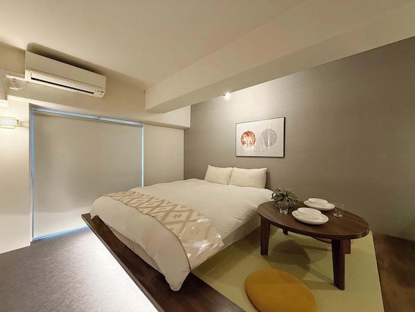 A modern bedroom with a bed, bedside table, and an air conditioning unit.