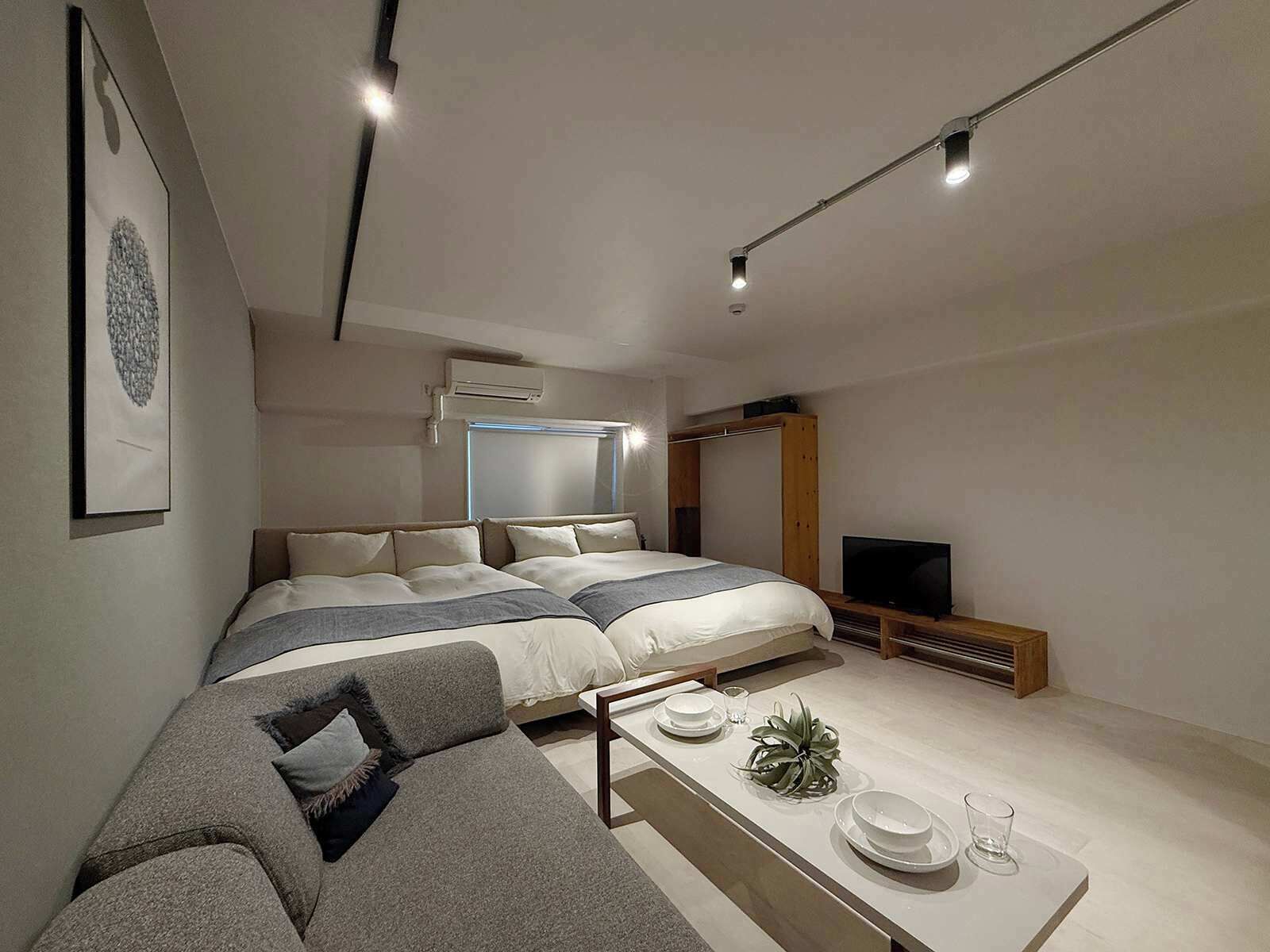 Un dormitorio moderno con una cama grande, un sofá, un televisor y un área de comedor con platos y vasos.