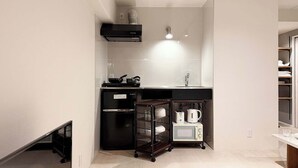 Eine kompakte Küche mit Mikrowelle, Wasserkocher und kleinem Kühlschrank.