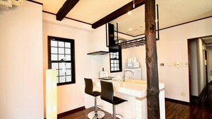A modern kitchen with two bar stools, a built-in stove, and a window with a grid pattern. - Next to Peace Park, Convenient Central Stay P61 (Hiroshima City)