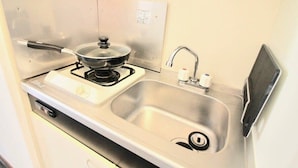 Une cuisine de taille réduite, équipée d’une cuisinière, d’un évier et d’un petit plan de travail.