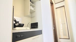 Une petite cuisine équipée d’un four à micro-ondes, d’une bouilloire et d’un petit plan de travail.