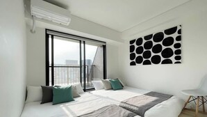 Habitación de hotel moderna con una cama grande, una ventana con persianas, un aire acondicionado de pared y un adorno mural geométrico.