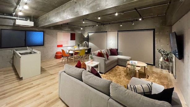Un soggiorno moderno con un divano grigio, un tavolino da caffè e una TV a parete.