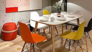 Una sala riunioni moderna con un'ampia pittura astratta, uno schermo per proiettore e sedie colorate.