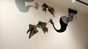 Een moderne woonkamer met een grijze bank, een bijzettafeltje met borden en een glas, en abstracte wanddecoratie.
