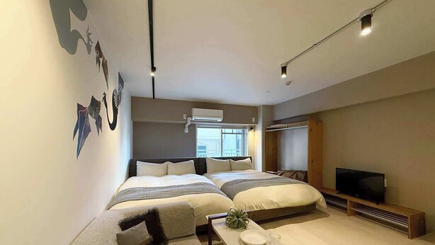 Een moderne hotelkamer met een groot bed, een bank, een televisie en een zithoek met borden en glazen.