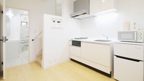 Une cuisine moderne avec des meubles blancs, un four à micro-ondes, un lave-vaisselle et un four encastré.