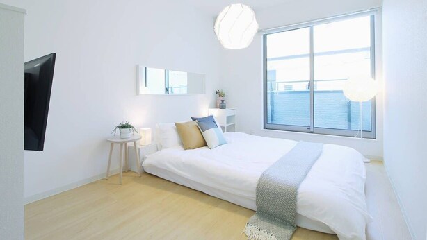 Un dormitorio moderno con una cama grande, una mesita de noche con lámpara, un candelabro colgante y un ventanal con vistas al agua.
