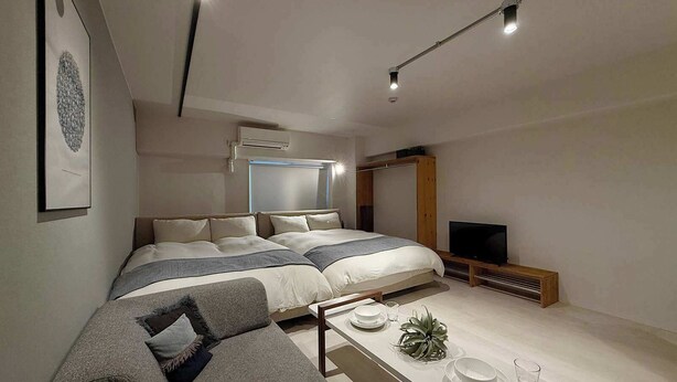 A modern bedroom with a large bed, a sofa, a TV, and a dining area with plates and glasses. - ORIGAMINN 502 by b hotel - 5 mins PeacePark (Hiroshima City)
