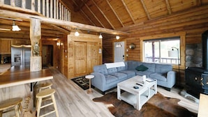 Interior de una cabaña de madera con cocina, comedor y sala de estar.
