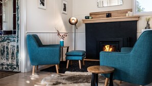 Un salón acogedor con sillones azul verdosos, una mesita de madera y una chimenea.