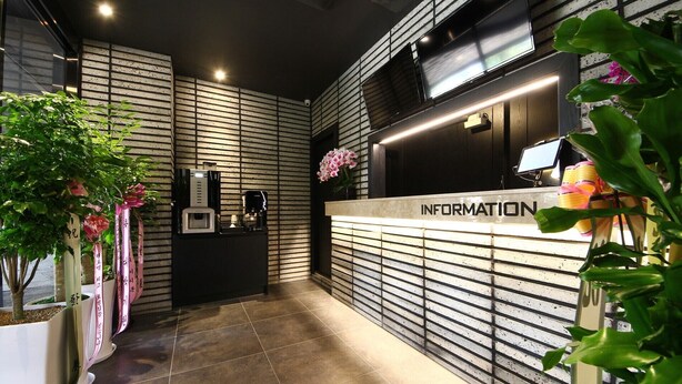 A reception area with a modern design, featuring a reception desk labeled "INFORMATION" and a digital screen above it. - Stay Month Hotel (Goyang)