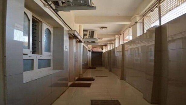 A long, narrow hallway with tiled floors and walls, leading to a door at the end. - Mourya Deluxe AC Lodge (Chitradurga)