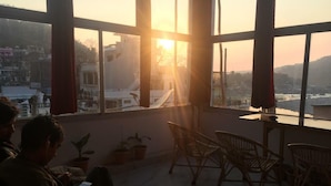 A room with large windows, a sofa, and chairs. - BlueStays Hostel (Yamkeshwar)