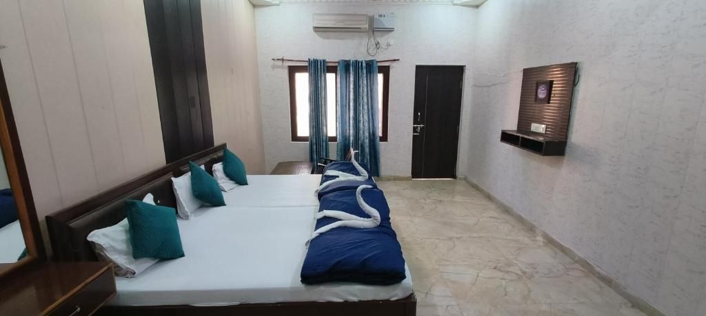 Habitación de hotel con una cama grande, un cabecero de madera, una mesita pequeña y un estante fijado a la pared.