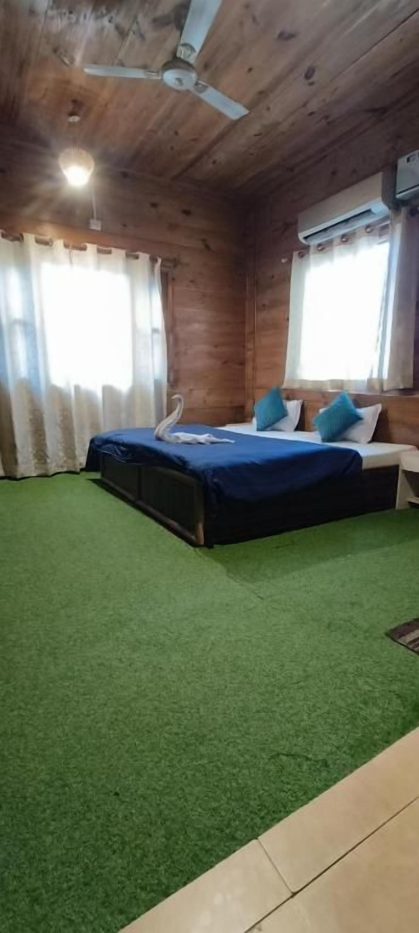 A room with a bed, a ceiling fan, and a window with curtains.
