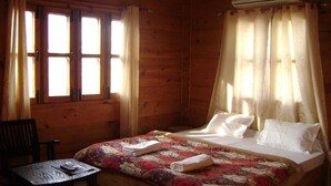 A wooden room with a bed, a table, and a chair. - BlueStays Hostel (Yamkeshwar)