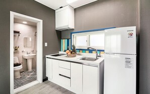 A modern kitchen with a white refrigerator, a sink, and a window above the counter.