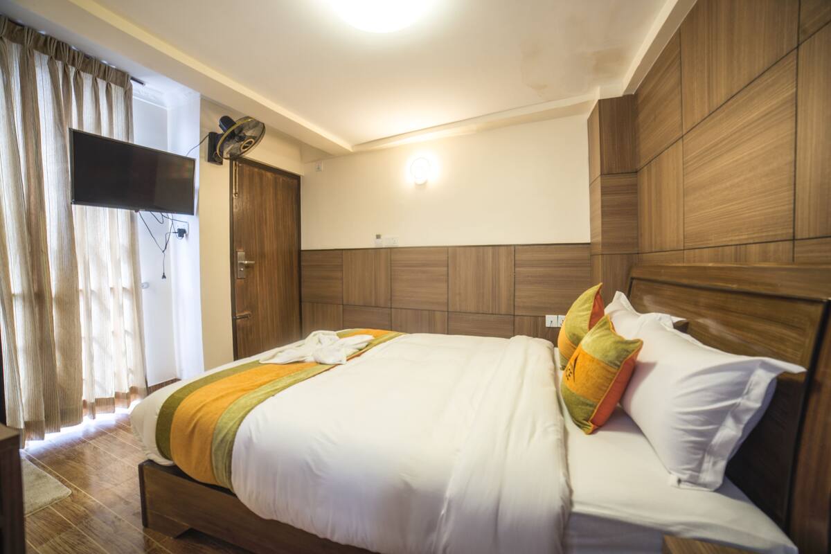 A hotel room with a large bed, wooden headboard, and a ceiling light.
