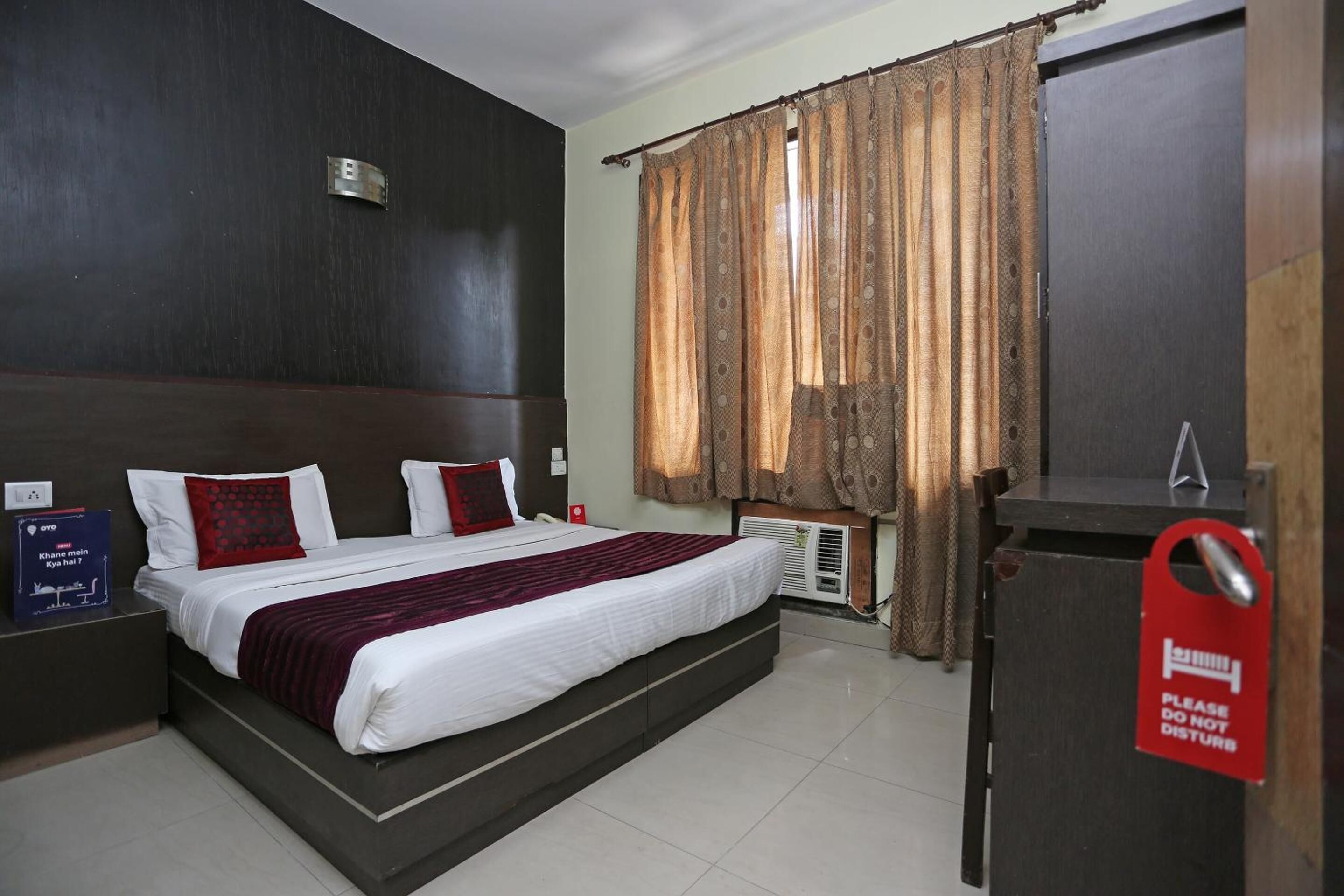 A hotel room with a large bed, a desk, and a wardrobe.