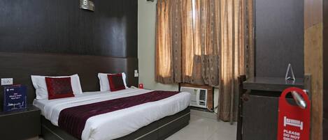 A hotel room with a large bed, a desk, and a wardrobe.