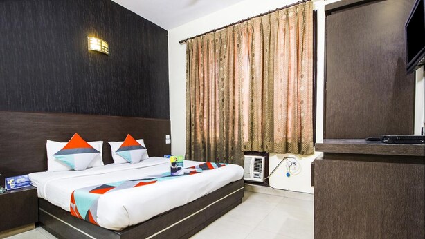 A modern hotel room with a large bed, a flat-screen TV, a desk, and a window with curtains. - Sunshine Residency (Noida)