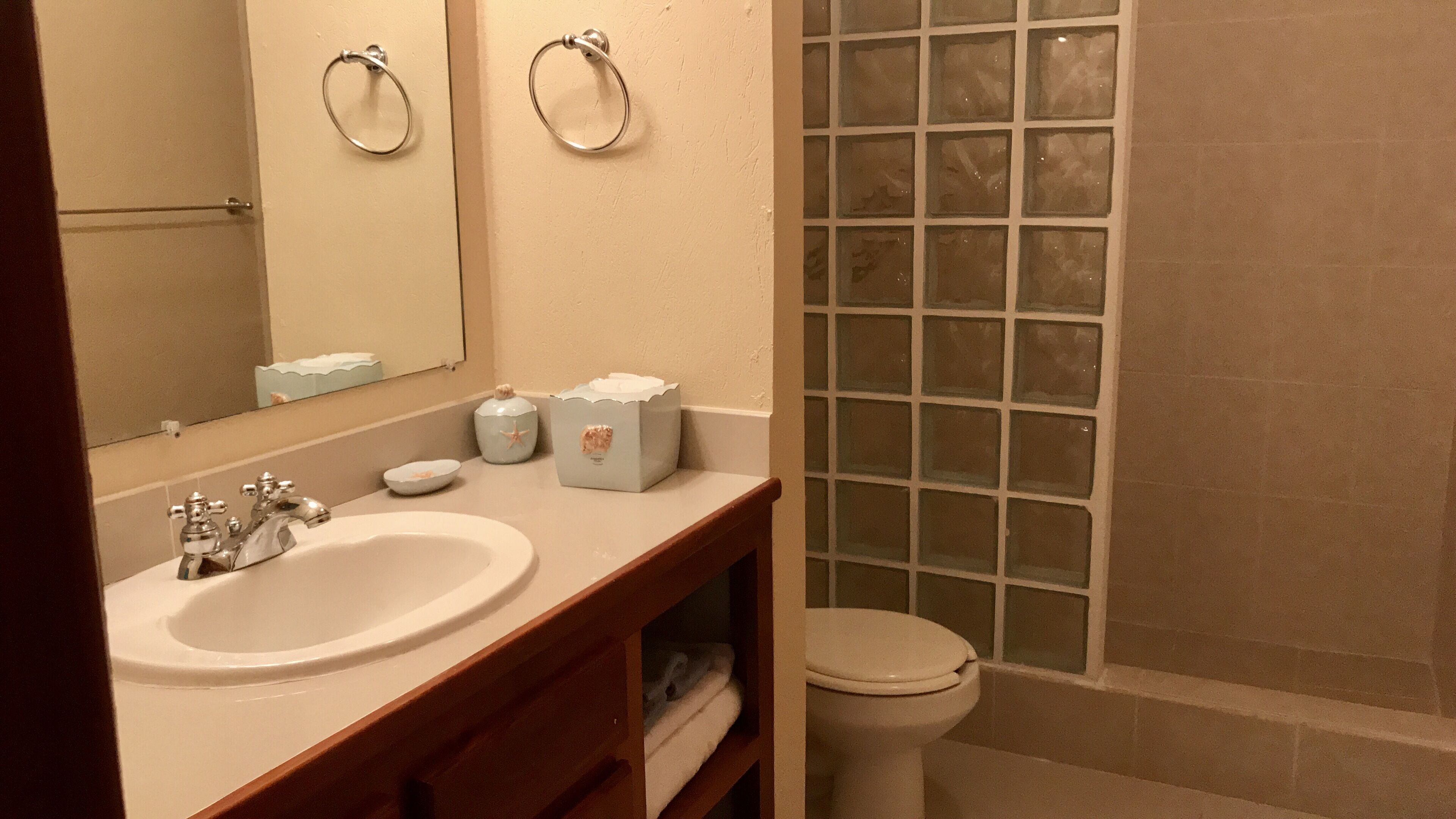 A bathroom with a sink, mirror, towel rack, and a glass shower enclosure.