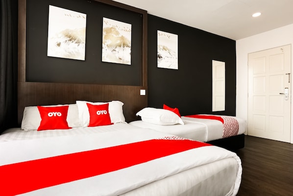 Une chambre d’hôtel avec deux lits, une literie rouge et blanche, et des œuvres d’art accrochées aux murs.