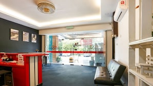 A reception area with a red counter, a black leather bench, and a view of the outside through a glass door.